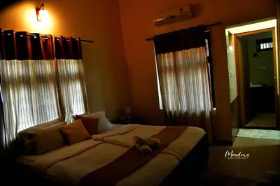 a bedroom with a large bed with two windows at Meadows Serene Retreat in Kannur