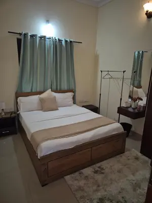 a bedroom with a large bed with a green curtain at Meadows Serene Retreat in Kannur