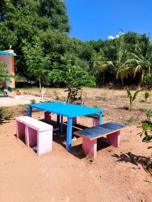 a picnic table and two benches in a field at GO2 Village Homestay in Pennāgaram