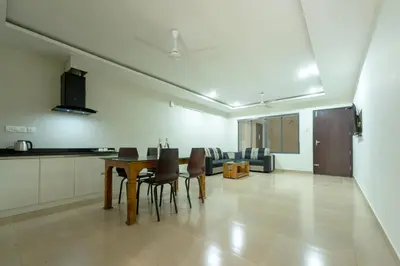 a kitchen and a dining room with a table and chairs at Span Avenue in Kozhikode