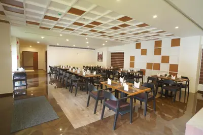 a restaurant with tables and chairs in a room at Hotel Devalokam in Trittāla