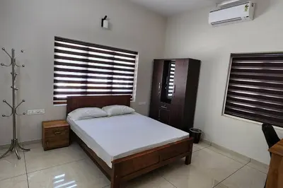 a bedroom with a bed and two windows at Nambiaparambil Serviced Villa in Kakkayam