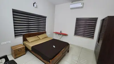 a bedroom with a bed and two windows at Nambiaparambil Serviced Villa in Kakkayam
