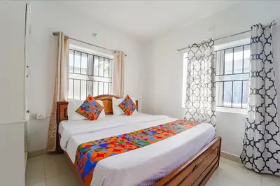 a bedroom with a bed and two windows at Via Bala Garden in Ooty