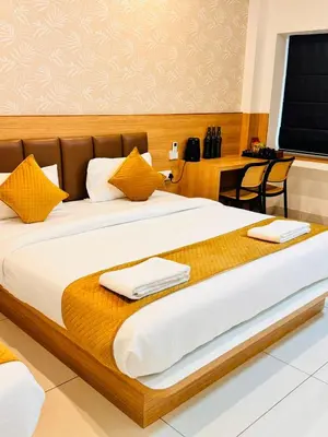 a bedroom with a large bed with two towels on it at Bimba Hotels in Mysore