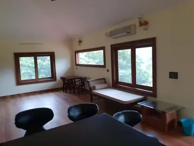 a living room with a table and chairs and windows at Tropical Blooms by StayApart in Kutta
