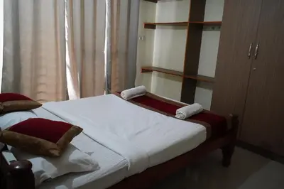 a bedroom with two beds and a book shelf at Golden Bells in Vānivilāsa Puram
