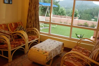 a room with chairs and a window with a view at Bella Vista Homestay in Coonoor
