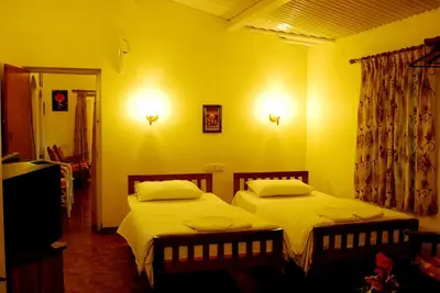 two beds in a room with yellow walls at Bella Vista Homestay in Coonoor