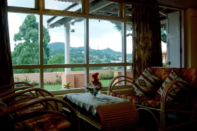 a living room with a table and chairs and a window at Bella Vista Homestay in Coonoor