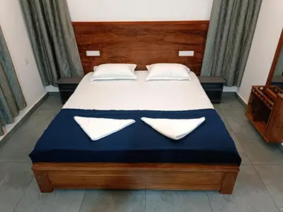 a bedroom with a large bed with white sheets and pillows at Aditi HOMESTAY in Kalpetta