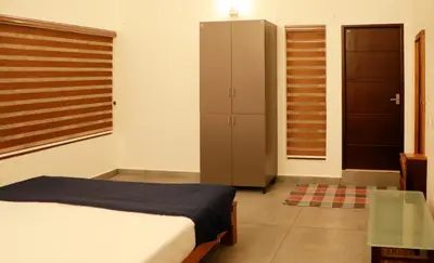 a bedroom with a bed and a cabinet and a table at Aditi HOMESTAY in Kalpetta