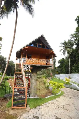 a tree house with a ladder in front of it at Karingens Resort in Malayāttūr