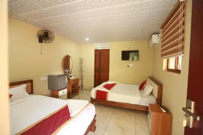 a hotel room with two beds and a television at Karingens Resort in Malayāttūr