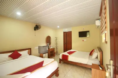 a hotel room with two beds and a television at Karingens Resort in Malayāttūr