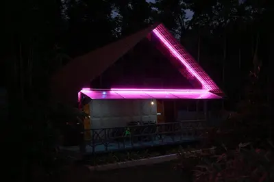 a house with a pink light on the roof at night at Karingens Resort in Malayāttūr