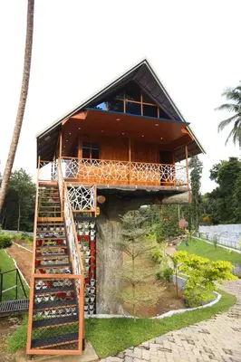a tree house with a staircase leading up to it at Karingens Resort in Malayāttūr