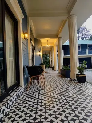 a porch with a chair on a building with columns at Villa Forever Coorg in Madikeri