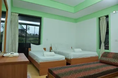 a bedroom with two beds and a couch and a window at Raahath Inn Munnar in Munnar