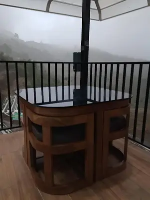 a wooden table on a balcony with a view at Orange Valley Farm Resort in Munnar