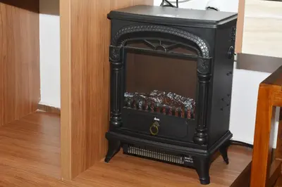 a small black stove in a corner of a room at Orange Valley Farm Resort in Munnar