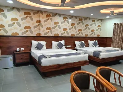two beds in a hotel room with two chairs at Dkgardenia24 in Kanakapura