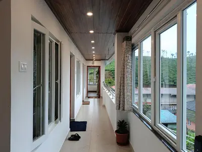 an empty hallway with large windows in a house at Hornbill Castle in Vālpārai