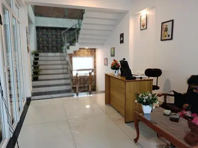 a living room with a staircase and a person sitting on a couch at Hornbill Castle in Vālpārai