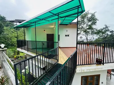 a house with a balcony with a green roof at Brooke hills falls view in Vallikavungal