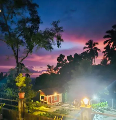 a view of a house with a sunset in the background at Brooke hills 2 BHK villa falls view in Vallikavungal