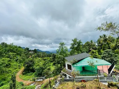 a small house with a blue roof on a hill at Brooke hills 2 BHK villa falls view in Vallikavungal