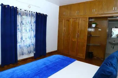 a bedroom with wooden cabinets and blue curtains at Pine Hood Villa in Ooty