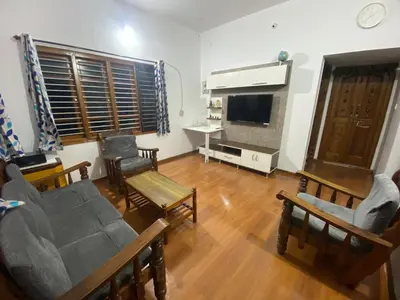 a living room with a couch and chairs and a television at Jk homestay Mysore in Mysore