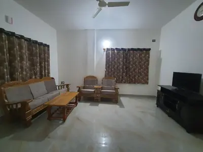 a living room with a couch and chairs and a television at Jk homestay Mysore in Mysore