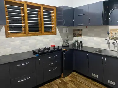 a kitchen with dark blue cabinets and a sink at Jk homestay Mysore in Mysore