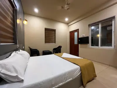 a bedroom with a bed and a window and chairs at Rocks beach house in Kannur