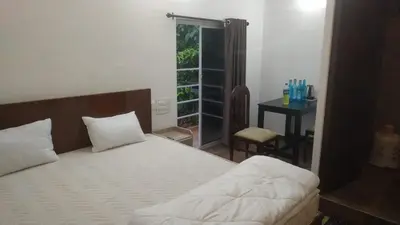 a bedroom with a bed and a table and a window at Randukai Farm House in Athirappally