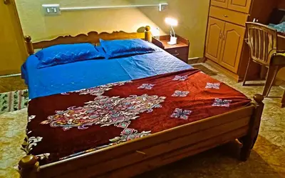 a bedroom with a bed with a red blanket on it at Rustic Retreat in Perumbavoor