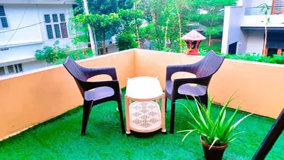 three chairs and a table on a balcony at Rustic Retreat in Perumbavoor