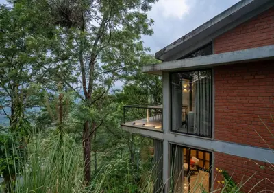 a brick house with a balcony and trees at LohonoStays Villa Amani 8B in Coonoor