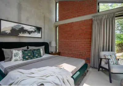 a bedroom with a bed and a brick wall at LohonoStays Villa Amani 8B in Coonoor