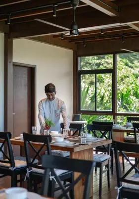 a man standing at a table in a restaurant at LohonoStays Amani Villa 9A in Coonoor
