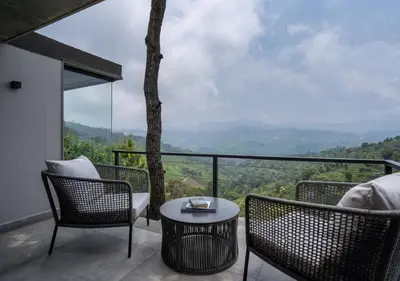 a balcony with chairs and a table and a view at LohonoStays Amani Villa 9A in Coonoor