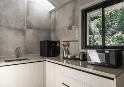 a kitchen with a microwave and a sink and a window at LohonoStays Amani Villa 9B in Coonoor