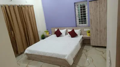 a bedroom with a bed with white sheets and red pillows at Eve Service apartment in Mysore
