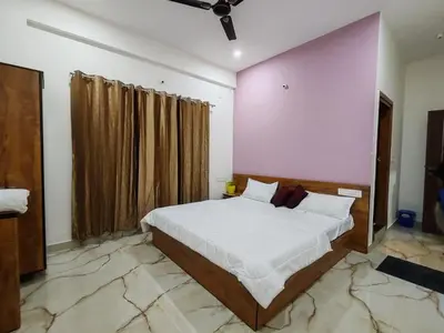 a bedroom with a large bed and a pink wall at Eve Service apartment in Mysore