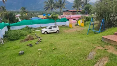 a white car parked in a yard with a playground at Alappat Lodge Masinagudi in Masinagudi