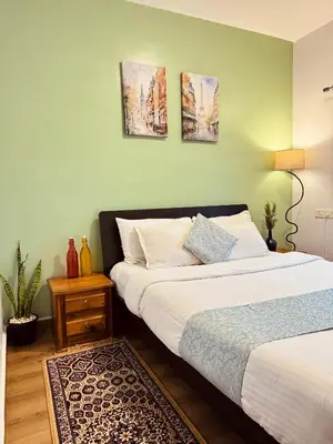 a bedroom with two beds and a green wall at Casa Serenity in Ooty