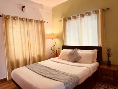 a bedroom with a bed with white sheets and a window at Casa Serenity in Ooty