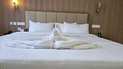 a large bed with white sheets and pillows at Prosland Hotel in Tirūr